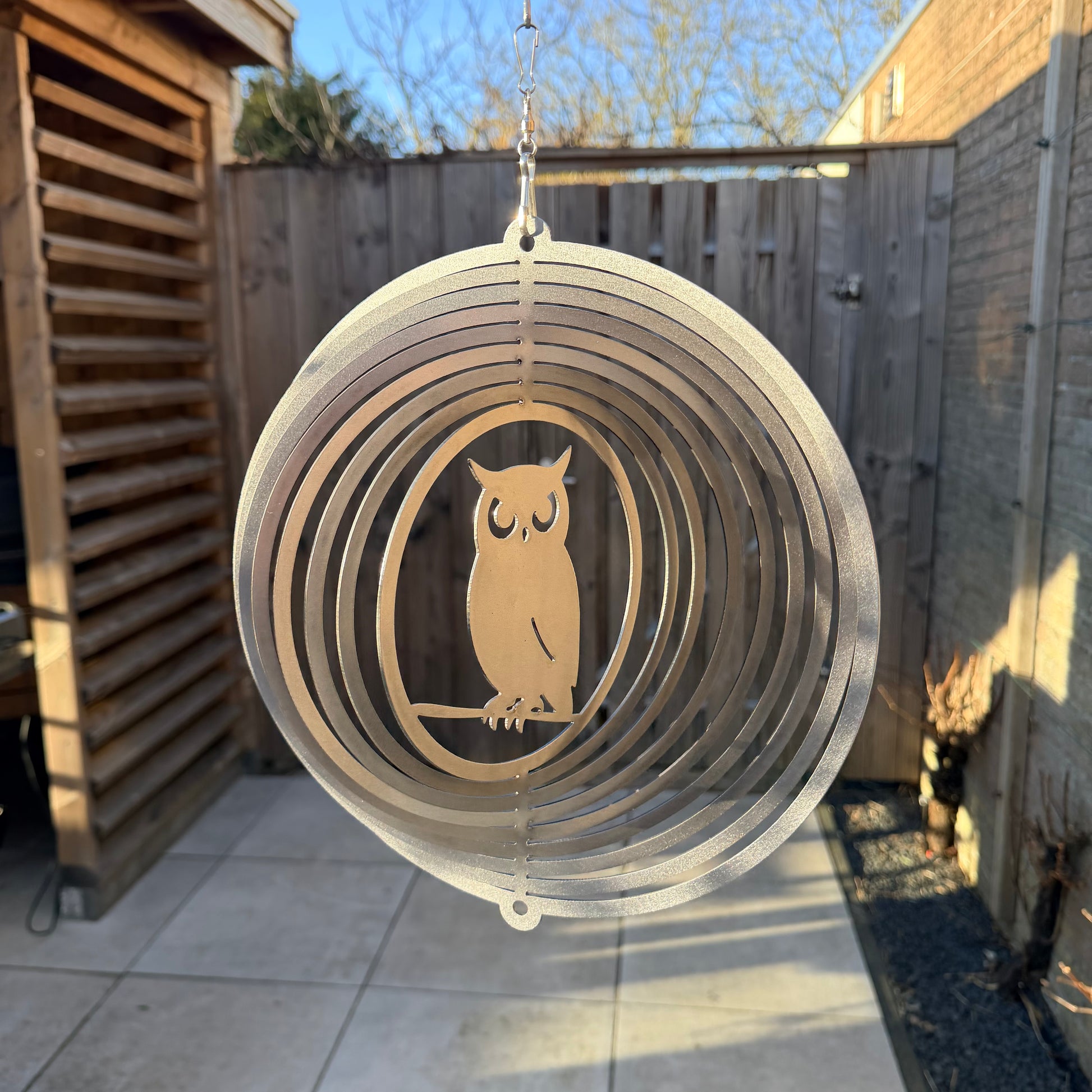 Wind Spinner Uil geborsteld staal hangend in een tuin